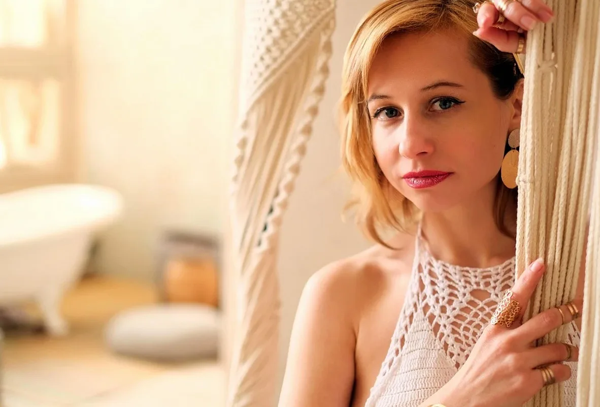 Woman in a white crochet halter top standing beside a macramé curtain